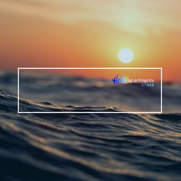 Olas al atardecer con el logo de Hello Apartments Sitges sobre el horizonte.