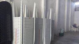 Pilhas de cadeiras brancas e pretas empilhadas em um armazém.