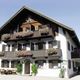Ein traditionelles Haus mit Holzbalkonen, geschmückt mit bunten Blumen, bei sonnigem Wetter.