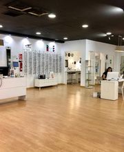 Óptica moderna con mostradores, gafas expuestas y dos personas trabajando en mesas.