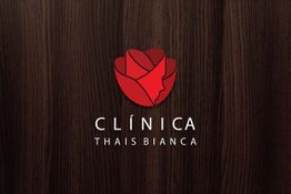 Logotipo vermelho de uma clínica no fundo de madeira. Texto: "CLÍNICA THAIS BIANCA".