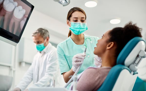 Zahnarzthelferin hält einen Sauger in der Hand.