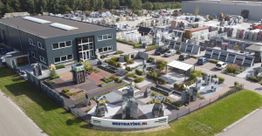 Bovenaanzicht van een showroom met bestratingsmateriaal en een groot magazijn.