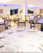 Sala di ristorante elegante con tavoli rotondi apparecchiati in bianco, pronta per un evento.