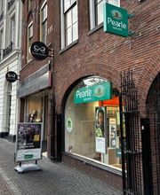 Winkelstraat met Pearle opticien en andere winkels in een rij, bakstenen panden.