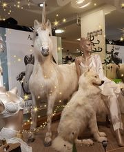 Schaufenster mit Schaufensterpuppen, einem Einhorn und einem Hund, umgeben von leuchtenden Punkten.