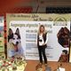 Frau vor Messestand für Tiernahrung mit Hundebildern und Produkten auf einem Tisch.