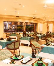 Restaurante elegante con mesas cubiertas por manteles verdes, sillas cómodas y decoración moderna.