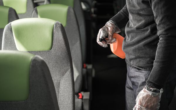 Mann reinigt Sitze im Reisebus mit Sprühflasche