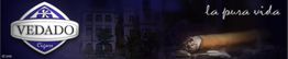 Logo "Vedado Cigars" mit Zigarette und Text "la pura vida" vor dunklem Hintergrund.