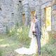Bride and groom standing together in front of stone ruins.
