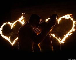 Paar küsst sich vor brennenden Herzen im Dunkeln.