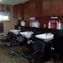 Hair salon interior with wash basins, chairs, and hair products on shelves and counters.