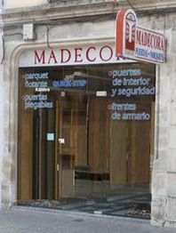 Fachada de tienda Madecor con productos de madera: parquet, puertas y frentes de armario.