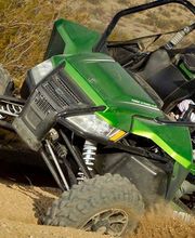 Persona conduciendo un vehículo todo terreno verde en un paisaje desértico.