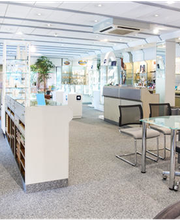 Optikergeschäft mit Brillenregalen, Beratungstisch und stufenlos zugänglichem, hellem Interieur.