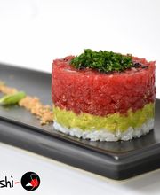 Tartar de atún, aguacate y arroz sobre plato negro, decorado con sésamo y wasabi.
