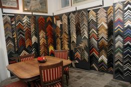 Ingelijste hoekmonsters op rekken, met een houten tafel en gestreepte stoelen op de voorgrond.