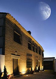 Edificio iluminado de noche con una gran luna en el cielo azul oscuro.