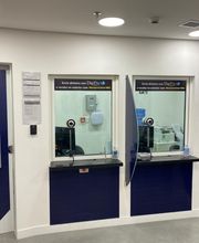 Porta azul com placas "Acesso Restrito" e "Sala VIP" ao lado de guichês de atendimento.