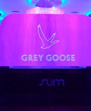 Mesa con logo de Grey Goose iluminada en tonos morados y azules en un ambiente moderno.
