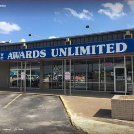 Storefront of Awards Unlimited beneath a clear, blue sky.