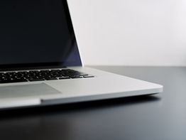 Un laptop aperto su un tavolo nero con schermo spento.