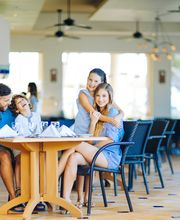 Personas en restaurante, con mesa servida, ambiente iluminado y diseño interior moderno.