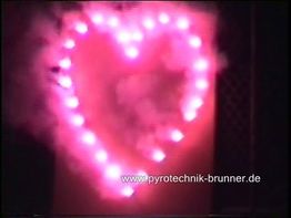 Herz aus roten Lichtern mit Rauch, Feuerwerk vor dunklem Hintergrund.