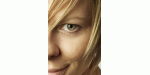 Nahaufnahme eines blonden Gesichts, leicht lächelnd, mit sichtbarem Auge und Haaren.