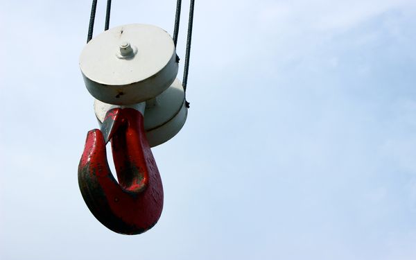 Ein roter Karabiner am Ende eines Lastenkrans, der die Mitarbeiter in ihrer Arbeit stark entlasten soll.