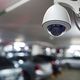 Security camera in a parking area with blurred cars in the background.