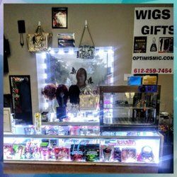 Store display with wigs, accessories, and a sign promoting wigs and gifts.