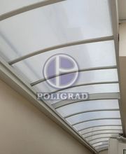 Cobertura curva de vidro e metal em área interna. Logo da Poligrad ao centro.