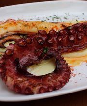 Tapa de pulpo a la plancha servido con aceite y pimentón sobre un plato blanco.