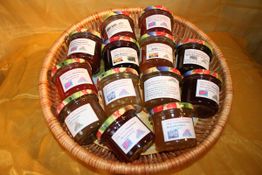 Korb mit verschiedenen Marmeladengläsern auf gelbem Hintergrund.