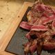 Bistecca alla fiorentina su tagliere di legno, cotta al sangue, su tavolo di marmo.