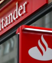 Fachada de uma agência do Santander com o logotipo branco em fundo vermelho.