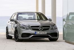 Auto sportiva grigia parcheggiata accanto a un edificio con vetrata riflettente.