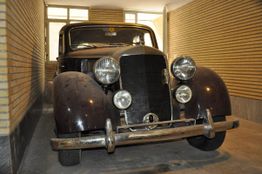 Ein klassisches Auto steht in einer Garage mit Backsteinwänden.