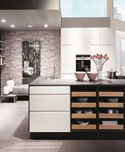 Cucina moderna con isola centrale, scaffali aperti e vista su grandi finestre luminose.