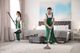 Two cleaners in green overalls vacuuming a carpet in a modern bedroom setting.