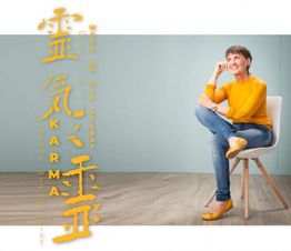Frau in gelbem Pullover auf Stuhl, neben Kunst mit den Worten "Karma" und "Werde, wer du bist".