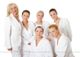 Sechs Frauen in weißen Roben vor einem weißen Hintergrund, lächelnd und freundlich.
