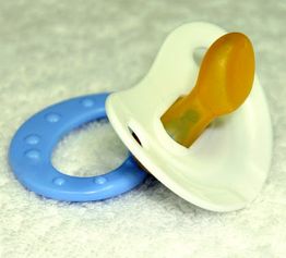 Blauer Babyschnuller mit weißem Schutzschild und gelbem Sauger auf weißem Hintergrund.