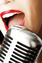 Nahaufnahme eines Mikrofons vor einem Mund mit rotem Lippenstift, der singt.