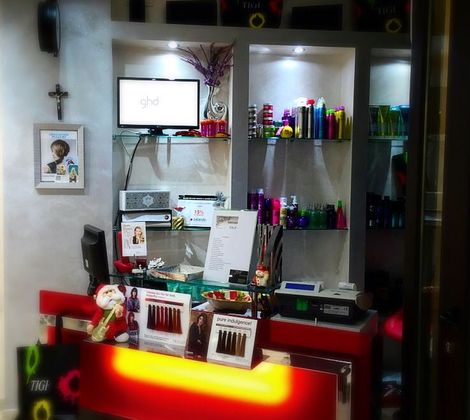 Interno di un salone di bellezza, con prodotti per capelli e un banco reception illuminato.
