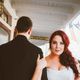 Bride in white gown holding groom's arm, standing on a porch.