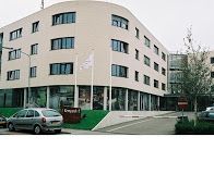 Modern kantoorgebouw met gebogen gevel en geparkeerde auto op de voorgrond.