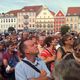 Menschenmenge schaut in die Ferne, bunte Gebäude im Hintergrund.
